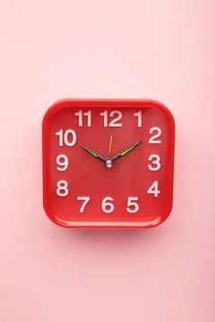 Red wall clock on pink background. Space for text Stock Photos