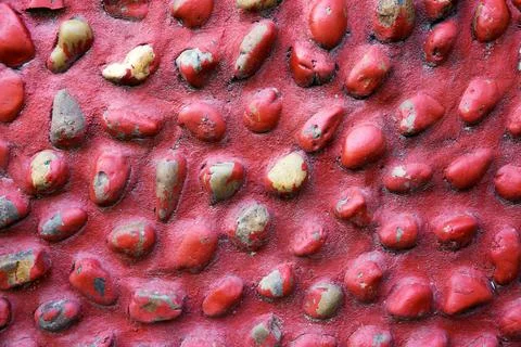 A red wall with a pattern of rocks on it Stock Photos