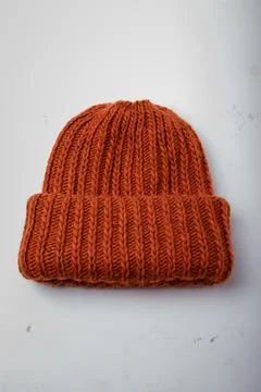 Red warm hat or cap knitted with braid pattern on white background, closeup Stock Photos