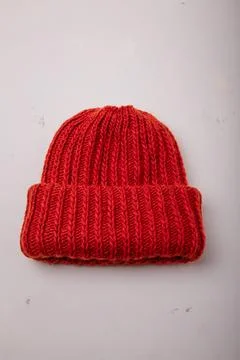 Red warm hat or cap knitted with braid pattern on white background, closeup Stock Photos