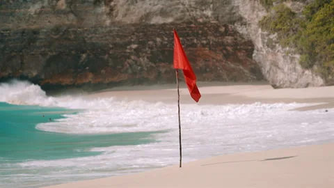 Red warning flag on Kelingking Beach with ocean waves Stock Footage 303394622