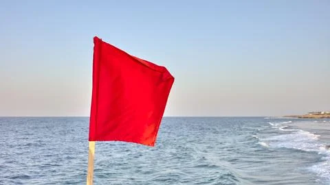 A red warning flag by the sea, selective focus. Stock Photos
