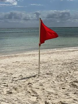 Red warning flag stands on sandy beach indicating hazardous water conditions Stock Photos