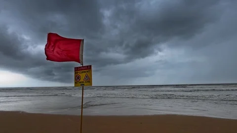 Red warning flag on a stormy beach with rough sea and dark clouds Vídeo Stock 340975105