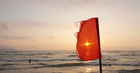 Red warning flag waving in the wind at sunrise, Danang beach, slow motion Stock Footage 345647156