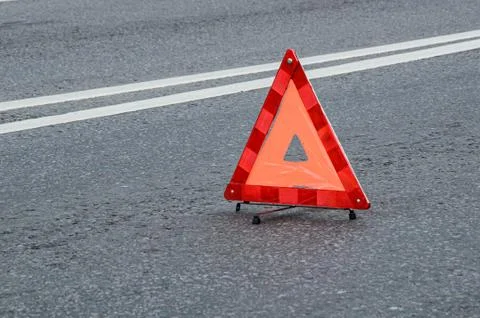 Red warning triangle on the carriageway with a double dividing strip. Stock Photos
