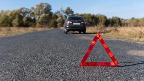 Red warning triangle on the road in front of a broken car. Breakdown of the car Foto stock