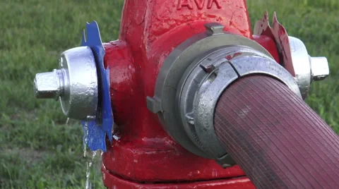 Red water hydrant on the street in use with fire hose attached Stock Footage