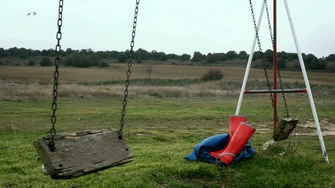 Red waterproof boots under a lonely swing Stock Footage 101512324