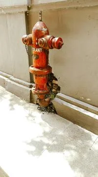 A red weathered fire hydrant mounted on a concrete sidewalk The image depi... Foto stock