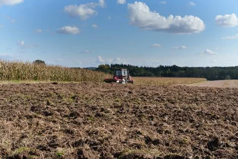A red wheeled tractor working in a field plows the soil. Stockfoto's