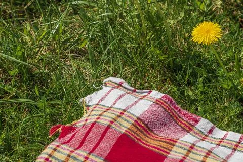 The red, white, and yellow patterned picnic blanket laid on green grass wit.. Stock Photos