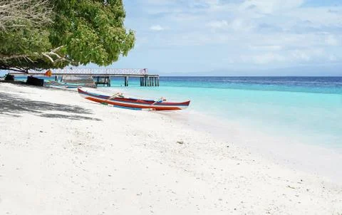 Red white blue colored small empty canoe boat stranded on tropical beach. Stock Photos