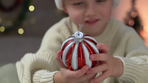 Red white Christmas ornament in sharp focus resting in small child hands while Stock Footage 322195751