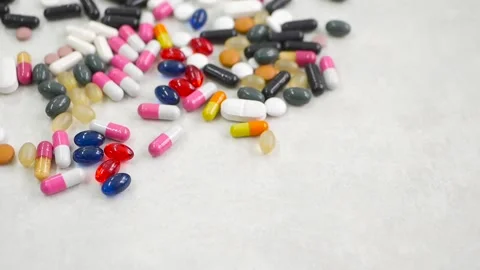 Red, white, colored pills on white bachkground Video stock 85742316