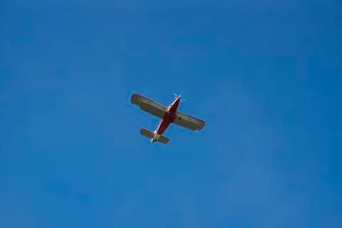 Red-white double wing propeller aircraft in the blue sky. Stock Photos