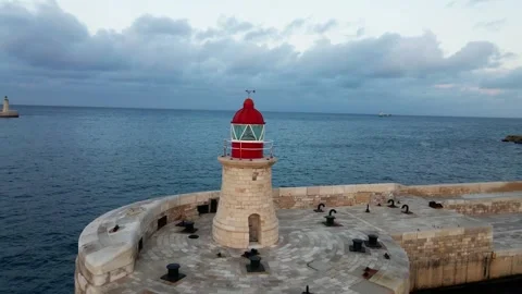 Red-white lighthouse in sea Circular movement around lighthouse Drone footage Stock Footage 233595519