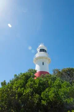 Red white lighthouse with sun reflection Stock Photos