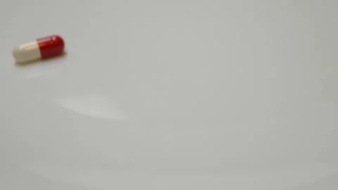 Red white pill rotate, close up A single pill laid out on a white surface Stock Footage 86177353