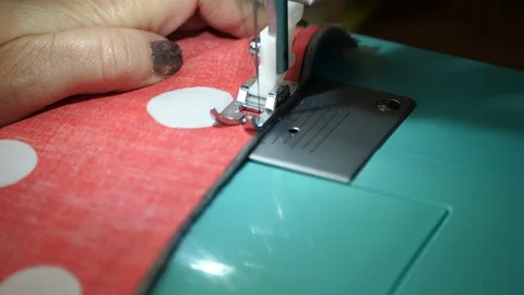 Red &amp; white polka dot material is fed through a sewing machine 動画素材 129519386