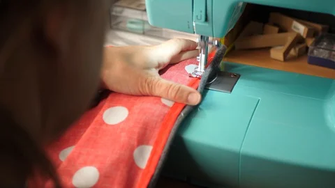 Red &amp; white polka dot material is fed through a sewing machine Stock Footage 129519700