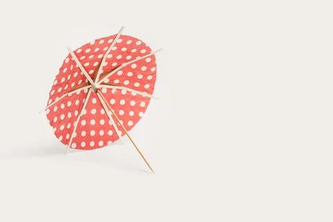 A red with white polka dots open cocktail umbrella on a white background Stock Photos