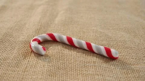 Red white striped candy cane is lying on woven burlap in flat design for food 스톡 사진