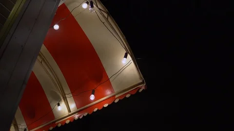Red white visor, cafe illuminated by light bulbs on the street. against the dark Stock Footage 91666365
