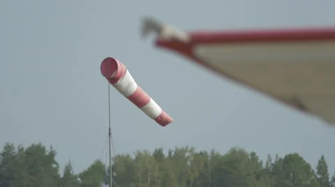 Red-white windsock flutters in the wind on a field near small aircrafts. Stock Footage 56182713