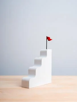 Red win flag on top of white staircase as bar graph chart steps on wood tab.. Stock Photos