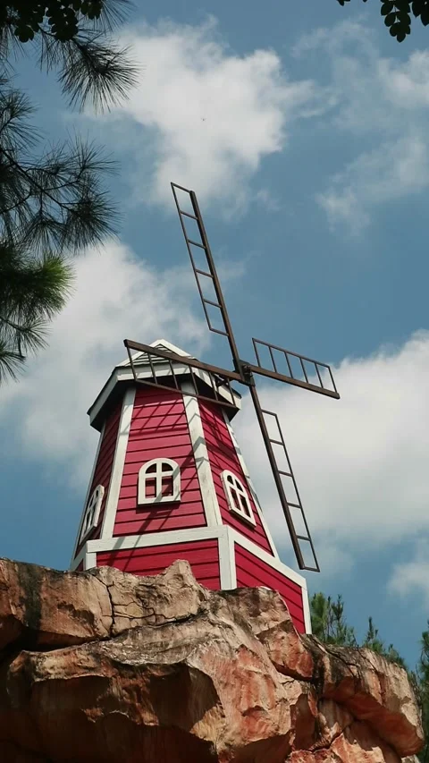 Red windmill standing on a rocky outcrop under a blue sky Stock Footage 333508089
