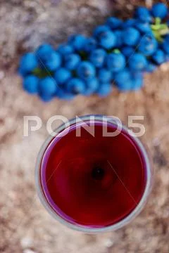Red wine and blue grapes laid on wooden stump Stock Photos