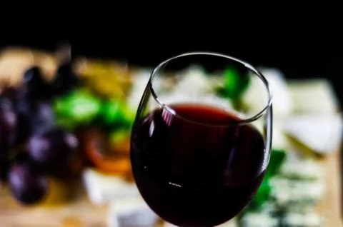 Red wine and set of different cheeses on a wooden board, delicious snack Stock Photos