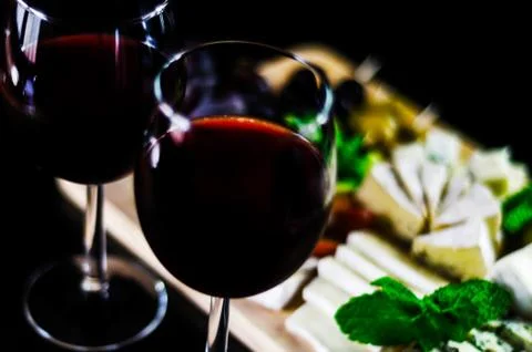 Red wine and set of different cheeses on a wooden board, delicious snack Stock Photos