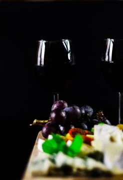 Red wine and set of different cheeses on a wooden board, delicious snack Stock Photos