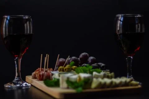 Red wine and set of different cheeses on a wooden board, delicious snack Stock Photos