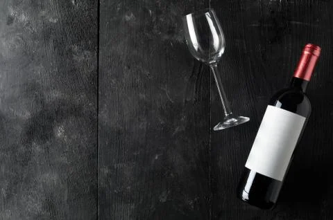 Red wine bottle with empty wine glass on dark wooden table flat lay from abov 스톡 사진