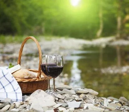 Red wine, cheese and bread served at a picnic. Mountain river background 스톡 사진