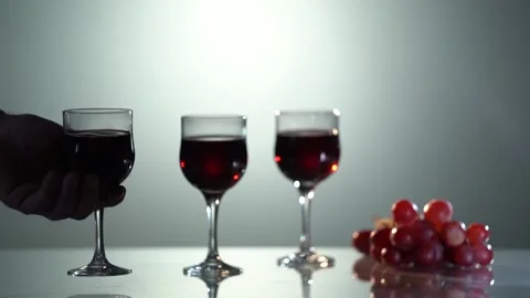 Red wine. Close-up man's hand holding the red wine glass. Hand with red wine in Stock Footage 153465202