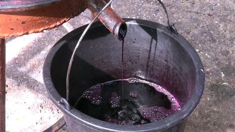 Red wine dripping into bucket from manual wine press Stock Footage 69783764