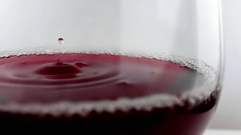Red wine drop falling down into drink glass on white background, nutrition Video stock 84140555