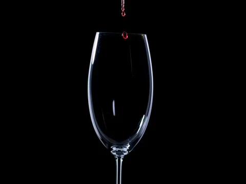 Red wine fills a glass on a black background Stock Footage