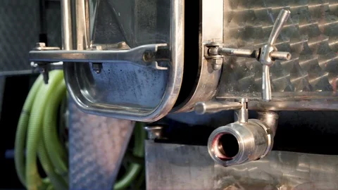 Red wine flows from the open door of the tank and from the tap in the winery Stock Footage 99105338