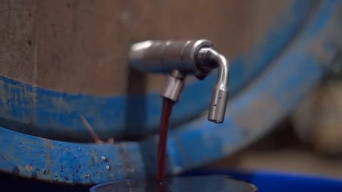 Red wine flows out from tap of a tank inside a wine cellar Stock Footage 87292028