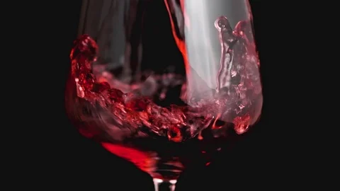 Red wine forms beautiful wave. Wine pouring in wine glass over black background Video stock 116910654