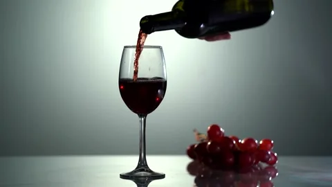 Red wine forms beautiful wave. Wine pouring in wine glass over white background Video stock 154306618