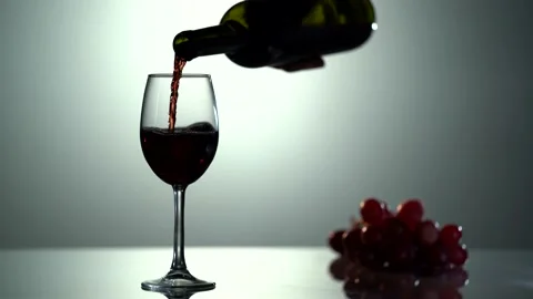 Red wine forms beautiful wave. Wine pouring in wine glass over white background Video stock 154450607