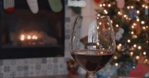 Red wine in front of Christmas decorations and a fireplace with stockings Stock Footage 259351537