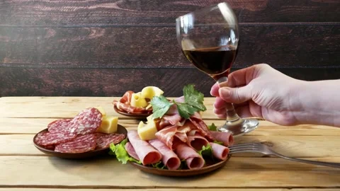Red wine in glass and cold smoked meat plate, antipasto set platter wooden pl Stock Footage 165322467