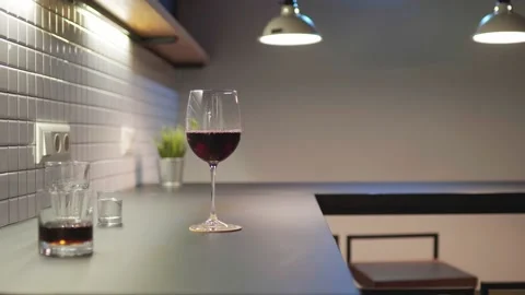 Red wine glass standing on a tabletop in kitchen Stock Footage 225044014